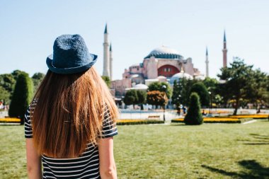 Istanbul, Türkiye'de ünlü Aya Sofya Camii yanındaki Sultanahmet Meydanı'nda arkadan şapkalı bir genç kız Gezgin.