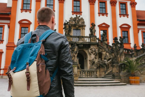 Путешественник с рюкзаком смотрит на туристическую достопримечательность. Турист смотрит на замок в Чехии. Осмотр достопримечательностей . — стоковое фото