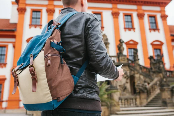 Cestovatel s batohem na zádech se dívá na mapě vedle hradu v České republice. Turistika a památky. Turista v krásné turistické místo. — Stock fotografie