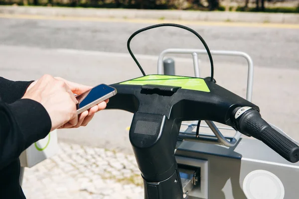 Egy férfi turista bérel egy bicikli vagy egy alternatív környezeti közlekedési mód, egy mobil alkalmazással a telefont. Vagy egyszerűen tárcsázhatunk egy számot, és kéri, vagy használja az internetet, az utcán. — Stock Fotó