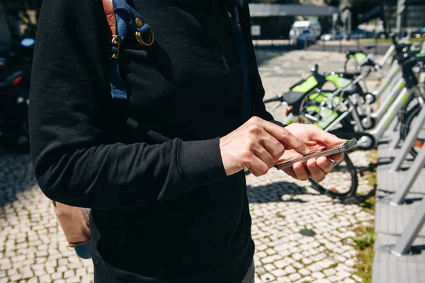 Un turista di sesso maschile noleggia una bicicletta o un mezzo di trasporto ambientale alternativo utilizzando un'applicazione mobile sul suo telefono. Oppure digita semplicemente un numero e chiama o usa Internet per strada . — Foto Stock