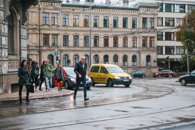 Riga, 4 Ekim 2017: Yağmurlu bulutlu juni yol çapraz insanlar. Yolda araba sürmek