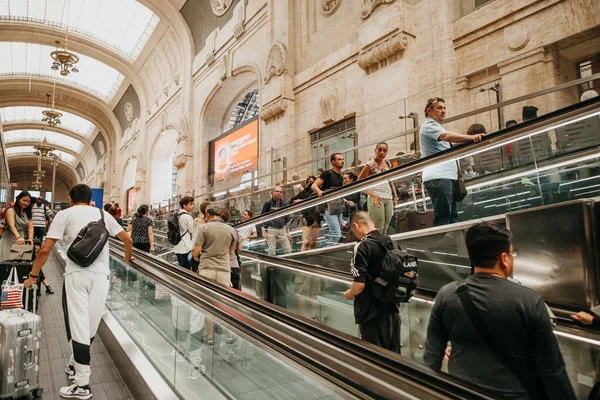 Mucha gente usa las escaleras mecánicas en la estación de tren de Milán . — Foto de Stock