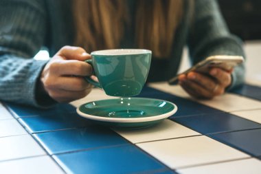 Kız içiyor ve cep telefonu kullanıyor..