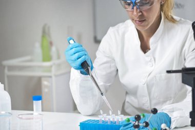Genç kadın bilim holding pipet koruyucu ekipman giyen laboratuarında