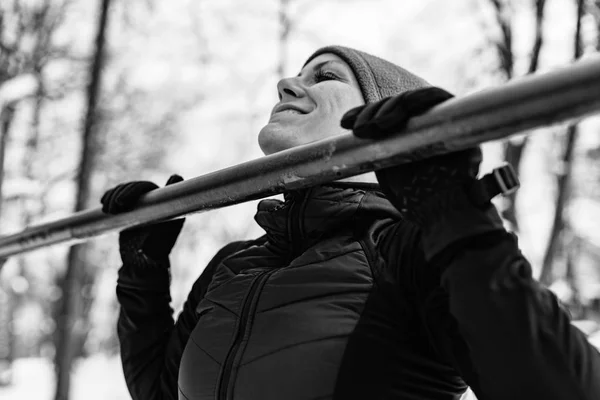 Female athlete exercising in park on winter day. Listening music and exercising