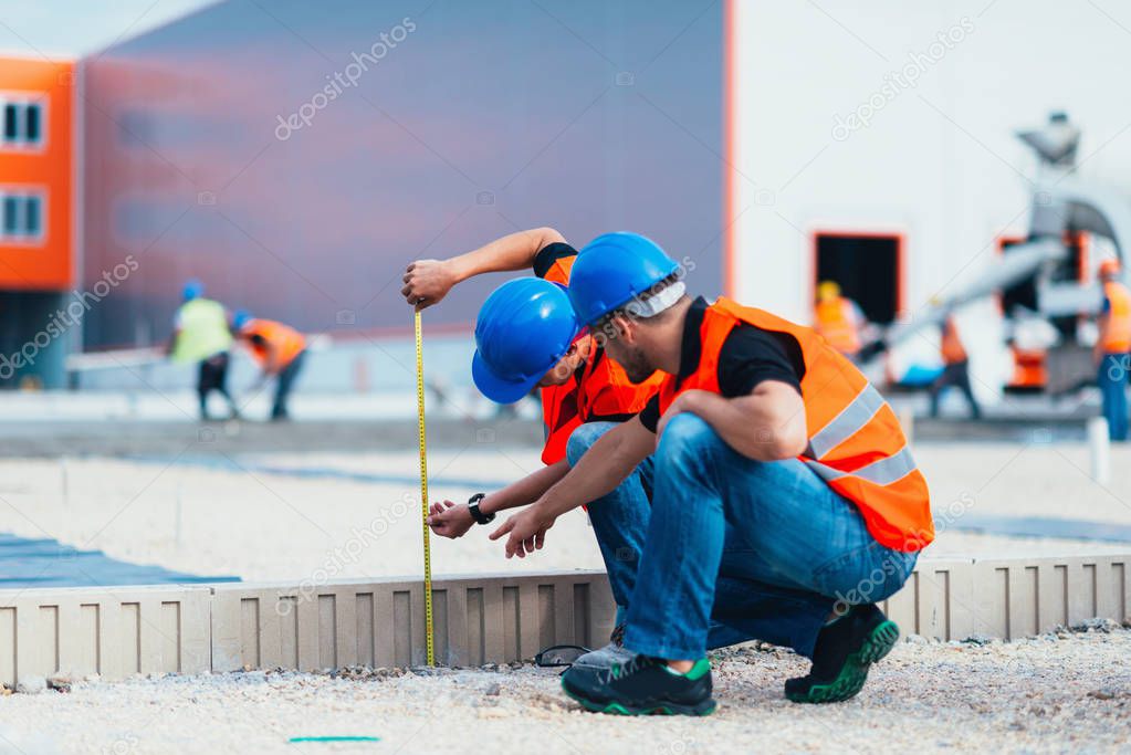 Construction workers measuring on construction site