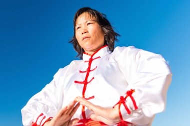 Asian woman practicing Tai Chi outdoors  clipart
