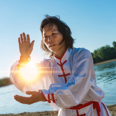 Asian woman practicing Tai Chi outdoors  clipart