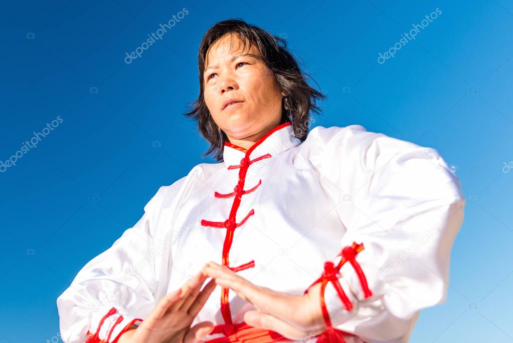 Asian woman practicing Tai Chi outdoors 