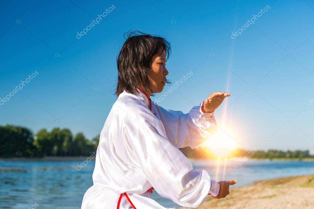 Asian woman practicing Tai Chi outdoors 