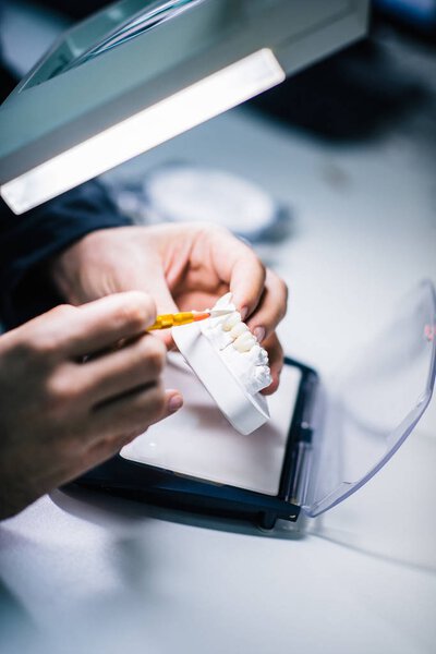 Dental technician or dentist working with tooth dentures in his laboratory