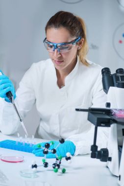 Kadın bilim araştırmacı laboratuarda mikro pipet kullanarak 
