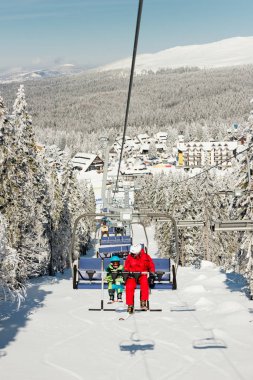 Küçük çocuğa teleferik ile kayak öğretim