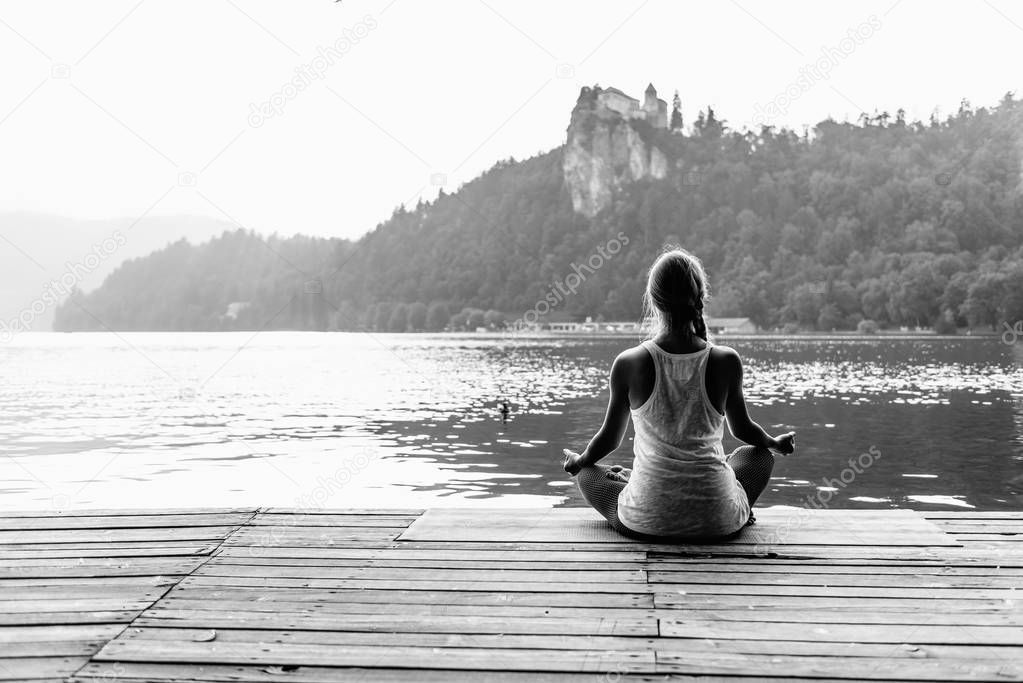 Female in lotus position. Meditating by the lake
