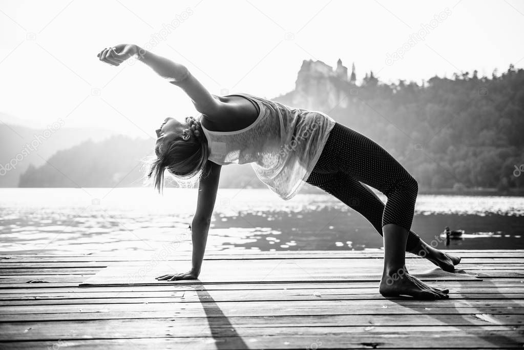 woman practicing yoga by the lake