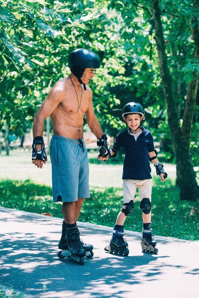 Dziadek Wnuczek Roller Skating Trzymając Się Ręce — Zdjęcie stockowe