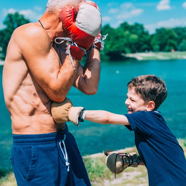 小男孩在湖边与祖父练习拳击 — 图库照片