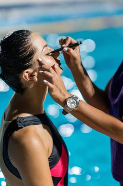 trainer Applaying make up before competition on synchronized swimming competition clipart