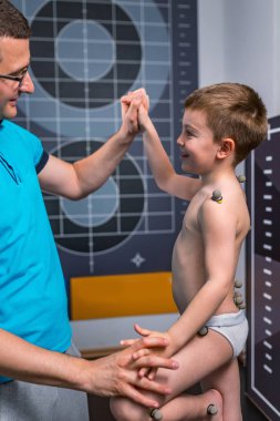 Fiziksel terapist ve topları sağlık kulübünde duruş analizi için işaretleme ile çocuk