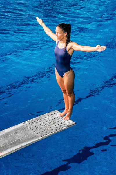女潜水员站在跳跃板上 准备跳入水池 — 图库照片