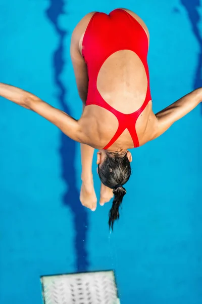 Female diver jumping into the pool from diving board