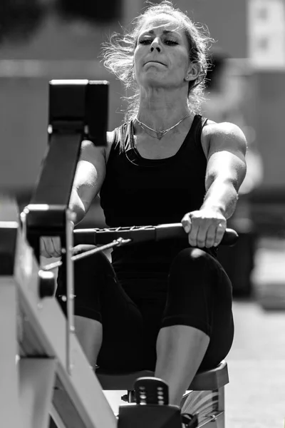 Female athlete on rowing machine on cross competition.
