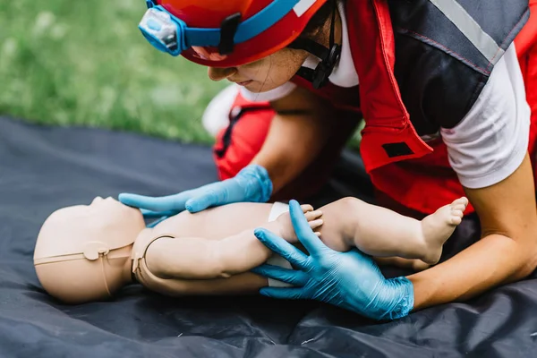 Cpr training of woman on baby dummy outdoors