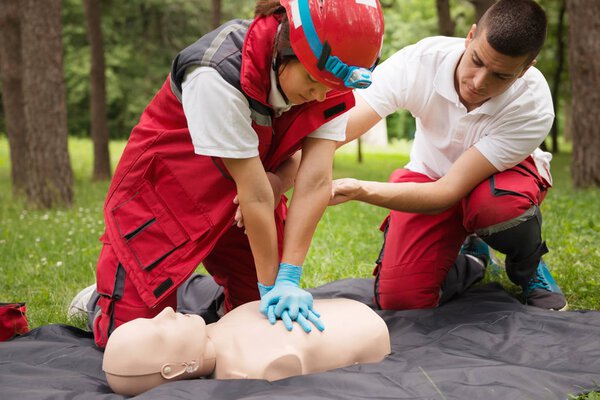 Cpr practice of woman and man on cpr dummy outdoors