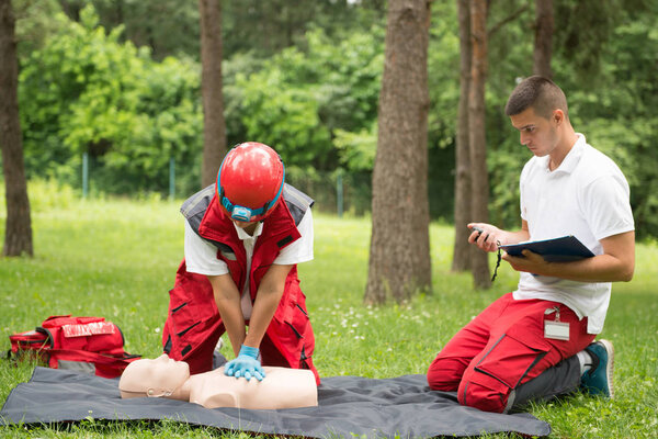 Cpr practice of woman and man on cpr dummy outdoors