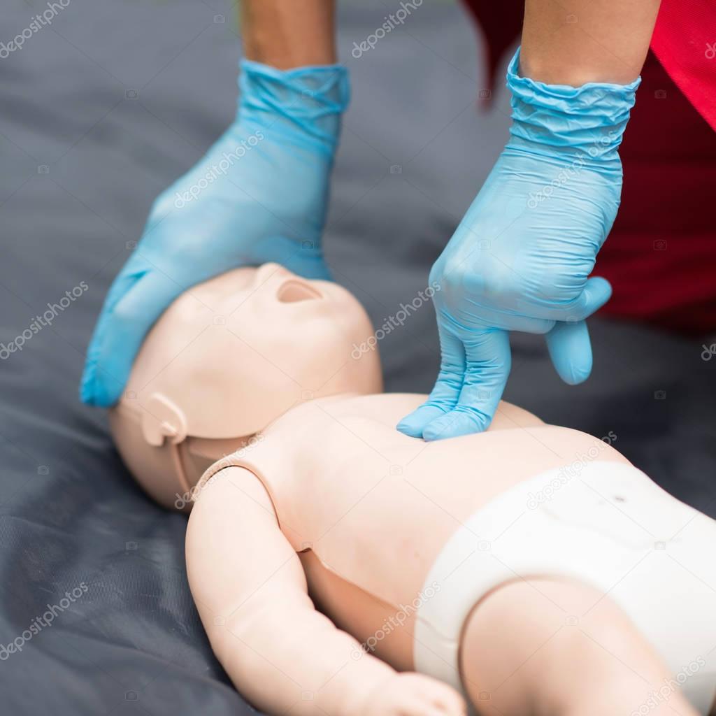 Cpr training of woman on baby dummy outdoors