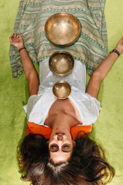 woman with Tibetan singing bowls using in sound therapy  clipart