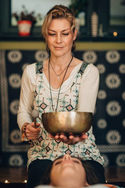 женщина, использующая Тибетскую чашу для пения в звуковой терапии
