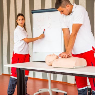 Kalp masajı sınıf konuşuyor ve ilk yardım, sıkıştırma oranı ve reanimasyon yordamı zekâ Cpr masaya kukla gösteren öğretim elemanları ile