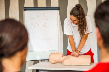 Kalp masajı sınıf konuşuyor ve ilk yardım, sıkıştırma oranı ve reanimasyon yordamı zekâ Cpr masaya kukla gösteren eğitmen ile