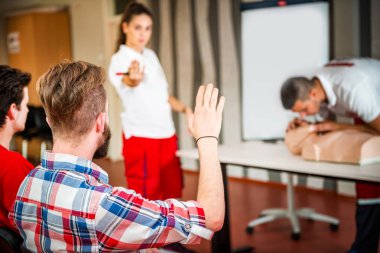 Kalp masajı sınıf konuşuyor ve ilk yardım, sıkıştırma oranı ve reanimasyon yordamı zekâ Cpr masaya kukla gösteren öğretim elemanları ile