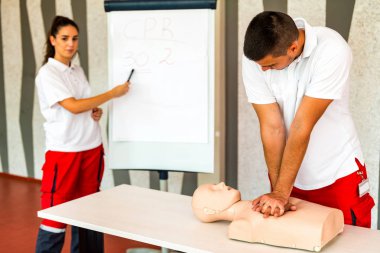 Kalp masajı sınıf konuşuyor ve ilk yardım, sıkıştırma oranı ve reanimasyon yordamı zekâ Cpr masaya kukla gösteren öğretim elemanları ile