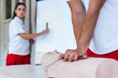Kalp masajı sınıf konuşuyor ve ilk yardım, sıkıştırma oranı ve reanimasyon yordamı zekâ Cpr masaya kukla gösteren öğretim elemanları ile