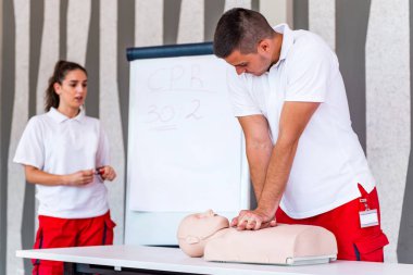 Kalp masajı sınıf konuşuyor ve ilk yardım, sıkıştırma oranı ve reanimasyon yordamı zekâ Cpr masaya kukla gösteren öğretim elemanları ile