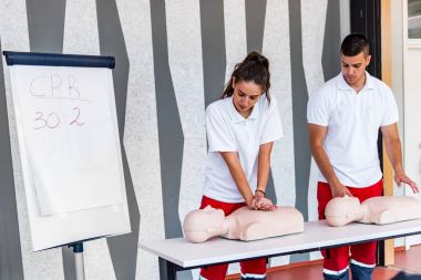 Kalp masajı sınıf konuşuyor ve ilk yardım, sıkıştırma oranı ve reanimasyon yordamı zekâ Cpr masaya kukla gösteren öğretim elemanları ile