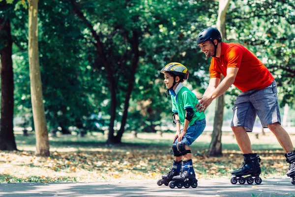 Father teaching son roller skating in park