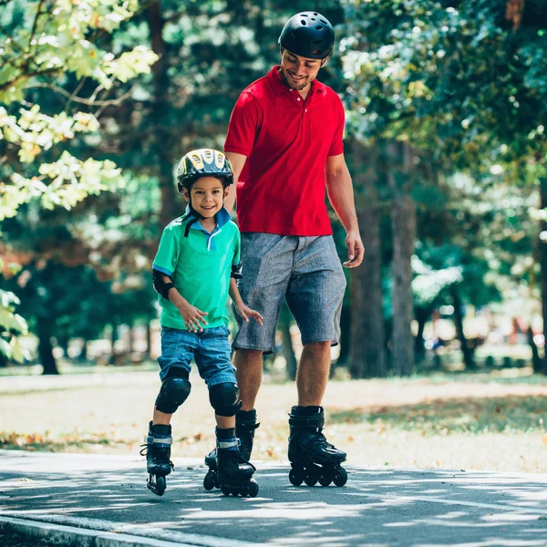 Father and son roller skating in park