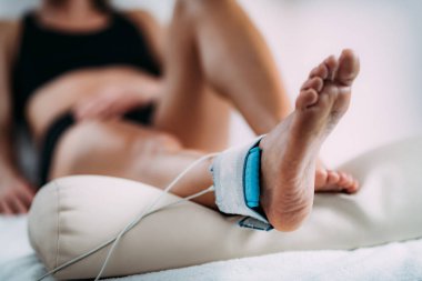 Onlarca, Fiziksel Terapide Transcutaneous Electrical Sinir Uyarımı. Hastanın ayak bileğine elektrot yerleştiren terapist.