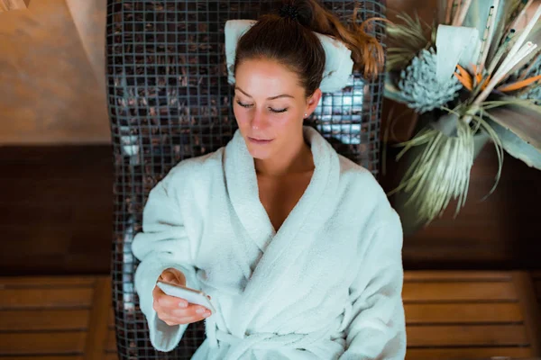 Mujer Albornoz Acostada Una Cama Tepidarium Usando Teléfono Inteligente — Foto de Stock