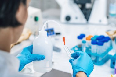 Toprak testi. Beyaz önlüklü kadın biyolog laboratuarda çözünmüş toprak örnekleriyle test tüpüne su döküyor. Toprağın Agrokimyasal incelemesi.