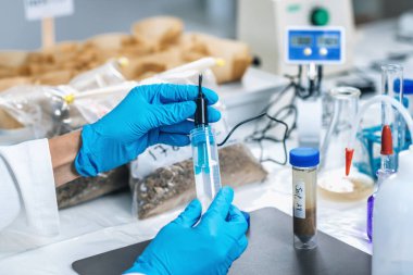 Toprak numunesinin ph 'sini elektronik ph metreyle ölçen bir bilim adamının ellerini kapat.. 