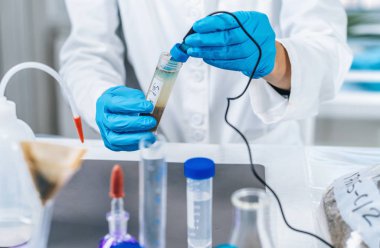Toprak numunesinin ph 'sini elektronik ph metreyle ölçen bir bilim adamının ellerini kapat.. 