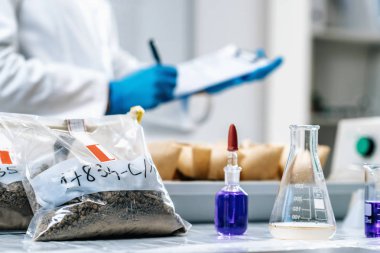 Toprak Örnekleri Test Laboratuvarı. Beyaz önlük giyen kadın bilim adamının laboratuarda notlar aldığı görüntüleri kapat..  
