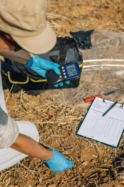 温度計で土壌温度を測定します 現場で土壌温度を測定する女性農学者 環境保全事業のフィールドワーク — ストック写真