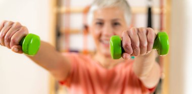 Halterle egzersiz yapan yaşlı kadının portresi. 